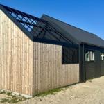 Moderne Holz- und Metallhaus mit schwarzem Dach und Fenstern.