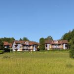 Villa mit Balkon und Terrasse im Grünen. Hintergrund: Wald und klarer Himmel.