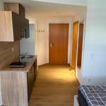 Küche mit Arbeitsplatte, Spüle und Schränken. Schlafzimmer mit Bett. Holzfußboden und Türen.
