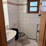 Badezimmer mit Toilette, Waschbecken und Heizkörper an der Wand.