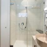 Dusche mit Duschbrause und Waschbecken mit Spiegel