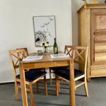Holztisch mit vier Stühlen, Wandbild und Küchenbuffet im Esszimmer.