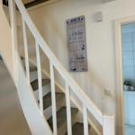 Treppenhaus mit weißer Treppe und Wanddekoration mit Seemotiven.