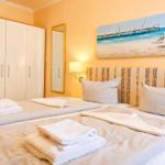 Schlafzimmer mit Doppelbett, Kleiderschrank und Strandbild an der Wand.