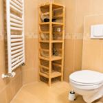 Badezimmer mit Toilette, Holzregal und Heizkörper an der Wand.