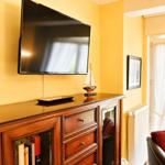 Wohnzimmer mit Fernseher, Holzschrank, Leuchtturm- und Segelschiffmodell sowie Sitzgelegenheit.