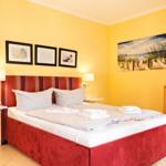 Schlafzimmer mit Bett, Wandbild und Schrank. Wände sind gelb gestrichen.