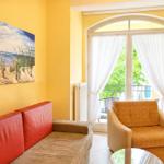 Wohnzimmer mit rotem Sofa, gelben Wänden und Blick auf Balkon