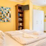 Schlafzimmer mit Bett, Bücherregal, Kleiderschrank und Fenster.