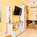 Wohn- und Essbereich mit Küchenzeile, TV und Wandbild mit Segelboot.
