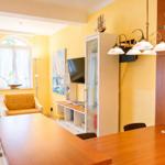 Wohn- und Essbereich mit Holztisch, gelben Wänden und Fernseher an der Wand.