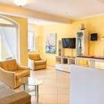Wohnzimmer mit gelben Wänden, Sitzmöbeln und TV. Balkon mit Türen. Wandbild und Schrank.