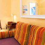 Sofa mit gestreiftem Kissen, Schreibtisch und Spiegel an der Wand.
