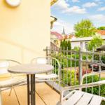 Terrasse mit Tisch und Stühlen, Vogelskulptur auf Geländer, Blick auf Wohngebiet mit Bäumen.