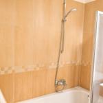 Bad mit Dusche, Badewanne und Waschbecken. Wandfliesen in beige.