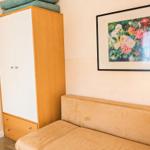 Schlafzimmer mit Kleiderschrank und Sofa. Wandbild mit Blumenmotiv.