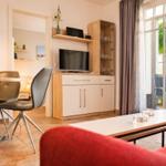 Wohn- und Essbereich mit TV, Schränken und Blick auf Balkon