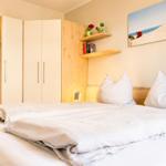 Schlafzimmer mit Bett, Kleiderschrank und Wandbild