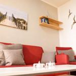Rotes Sofa mit Kissen, Wandbild und Regal mit Büchern