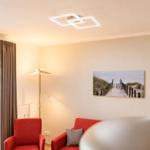 Ein Wohnzimmer mit roten Sesseln, Wandbild und Bodenheizung.