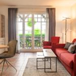 Wohnbereich mit rotem Sofa, Couchtisch und Blick auf Balkon