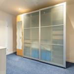 Schlafzimmer mit Schiebetüren-Schrank und blauem Teppichboden.
