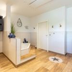 Bad mit Badewanne, Holzfußboden und Schrank. Wanduhr und Strandbild an der Wand.