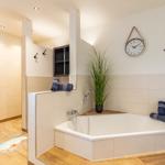 Bad mit Badewanne, Dusche und Pflanze. Wanduhr und Handtücher sind sichtbar.