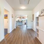 Hallenflur mit Holzboden, Schrank und Spiegel. Durchgänge zu Küche und Schlafzimmer.