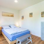 Schlafzimmer mit Bett, Nachttischen und Kleiderschrank. Wandbilder mit Meeresmotiven.