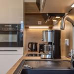 Küche mit Spüle, Kaffeemaschine, Herd und Backofen.