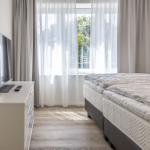 Schlafzimmer mit Doppelbett, TV und Fenster mit Vorhängen.