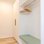 Schrank mit Kleiderständer und Sitzbank in einem Schlafzimmer
