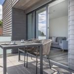 Terrasse mit Tisch und Stühlen. Durch Glastür ist Wohnzimmer mit Sofa sichtbar.