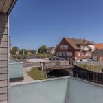 Blick von Balkon auf Kanal und rote Backsteinhäuser unter blauem Himmel.