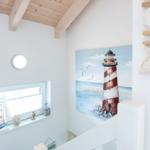 Wohnbereich mit Holzdecke, Seemotiv-Bild und Fenster mit Segelboot.