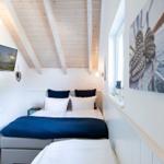 Schlafzimmer mit Bett, Fernseher und Wandbild an der Seite.