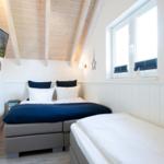Zimmer mit Doppelbett, Einzelbett, Fenster und TV an der Wand.