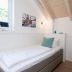 Schlafzimmer mit Einzelbett, Fenster und Holzdecke.