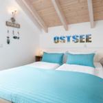 Schlafzimmer mit Bett, Nachttischen und Holzdecke. Wandbild OSTSEE und BEACH HOUSE Dekoration.