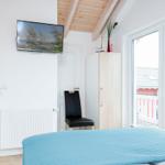 Schlafzimmer mit Bett, TV und Balkonansicht