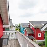 Terrasse mit Blick auf bunte Häuser und Garten.