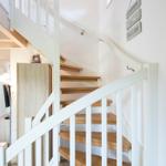 Eine Treppe mit Holzstufen und weißem Geländer führt zur oberen Etage.