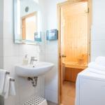 Badezimmer mit Sauna, Waschbecken und Toilettenbereich.