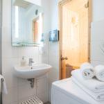 Badezimmer mit Waschbecken, Spiegel, Sauna und Handtüchern.