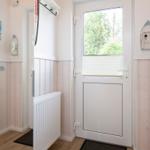 Eingangsbereich mit weißen Wänden, Holzverkleidung und Fenster zur Außenseite.