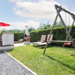 Hinterhof mit Grill, Liegestühlen, Schaukel und rotem Sonnenschirm.