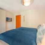 Schlafzimmer mit Bett, Kleiderschrank und Wand-TV.