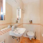 Badezimmer mit Waschbecken, Spiegel, Toilette und Fliesenverkleidung.