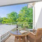 Terrasse mit Tisch, Stühlen und Blick auf Bäume.